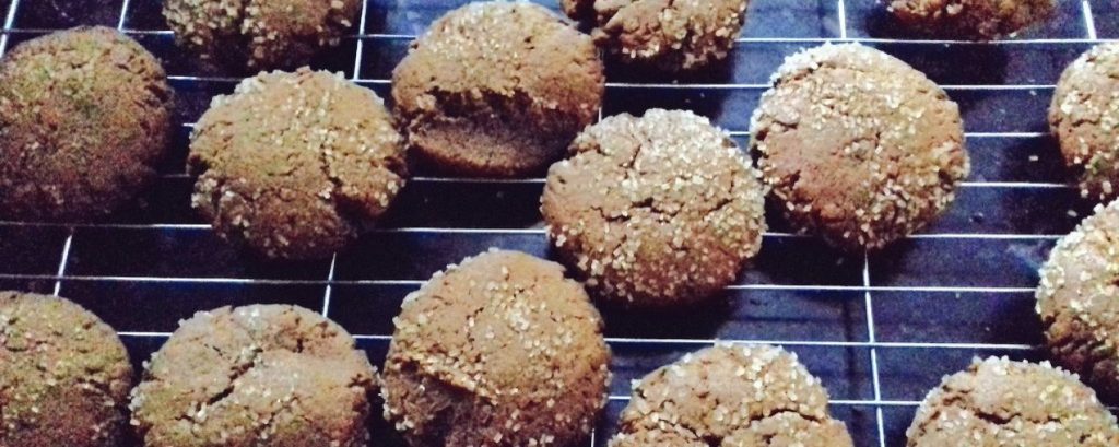 Ginger cookies on a wire rack on a black surface.