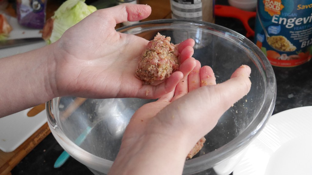 Alex holds a sausage shaped patty in her left hand over the bowl. 