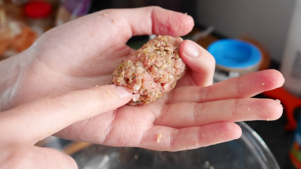 Alex pushes the end of the sauage in.