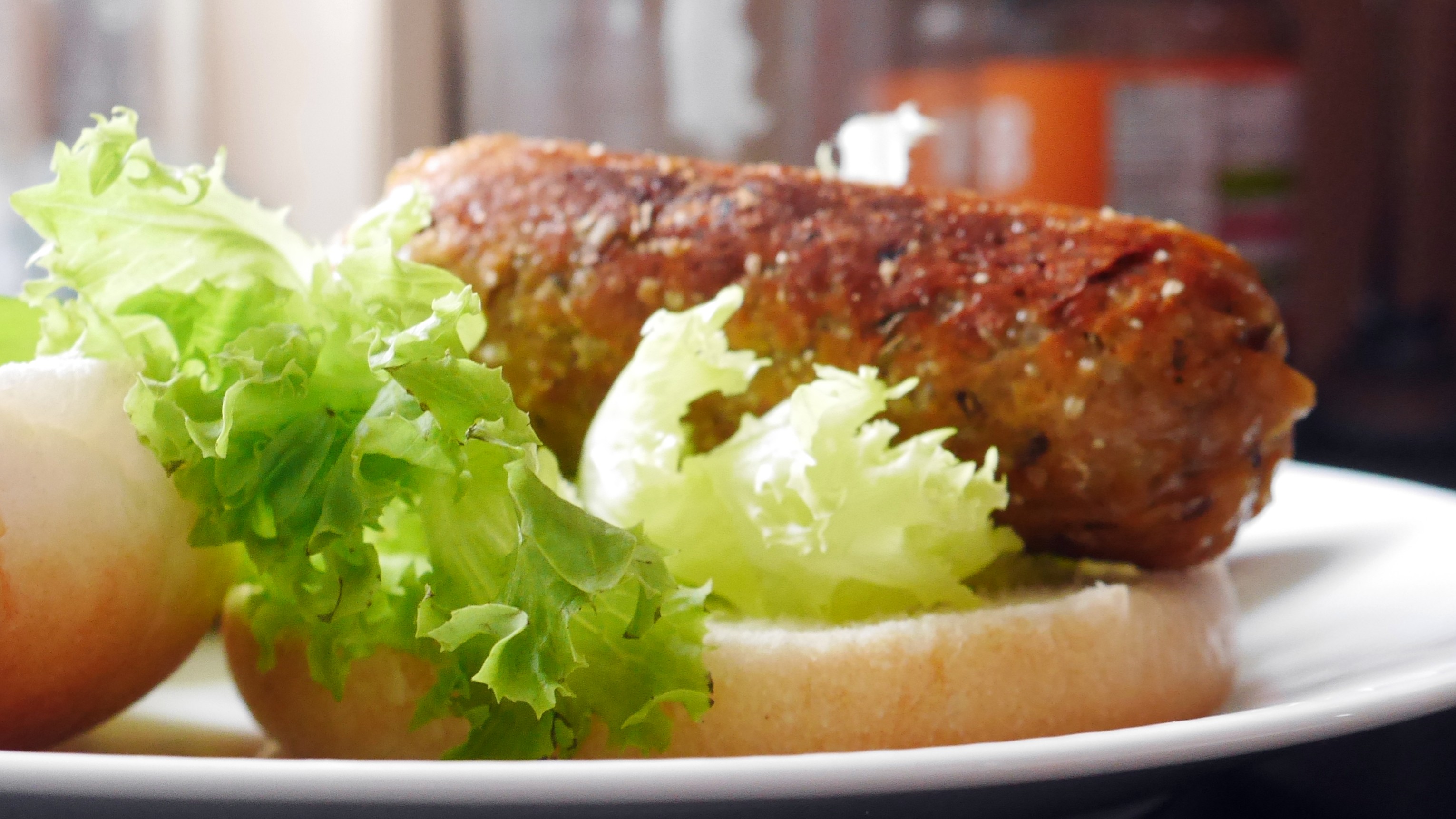 Seitan sausage on a white roll with lettuce